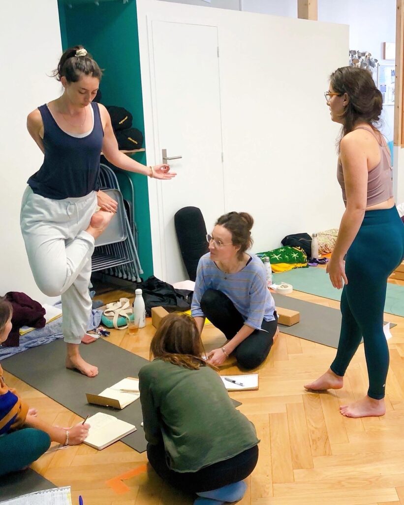 Stagiaires en formation de professeur de yoga observant une posture et prenant des notes